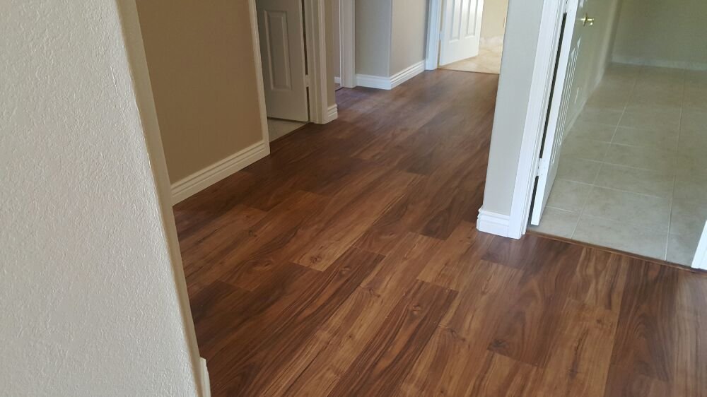 Hallway with grey wall paint and dark walnut colored luxury vinyl flooring leading to doorway